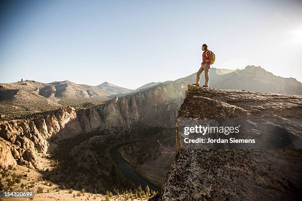 a man standing on top of a tall cliff. - smith rock state park bildbanksfoton och bilder