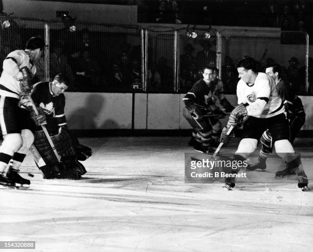 Goalie Johnny Bower of the Toronto Maple Leafs tries to make the save on Gordie Howe of the Detroit Red Wings during their game circa 1959 at the...