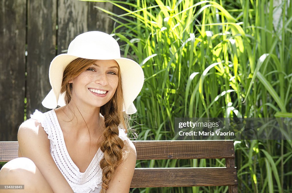 Smiling young woman sitting on bench, portrait
