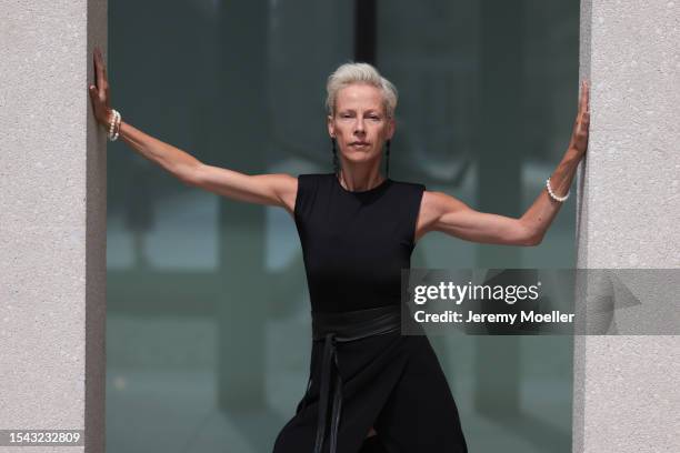 Martina Gleissenebner is seen wearing long black earrings with rhinestones, a black sleeveless midi dress with black leather belt and a front split,...