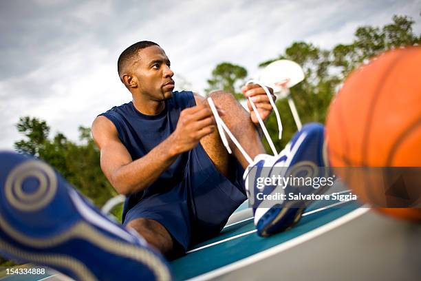 young man tying his shoelaces - basketball shoe fotografías e imágenes de stock