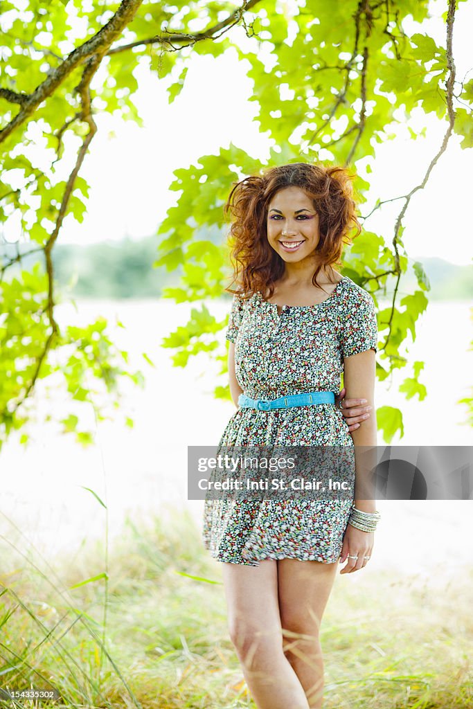 Happy, smiling woman standing under tree