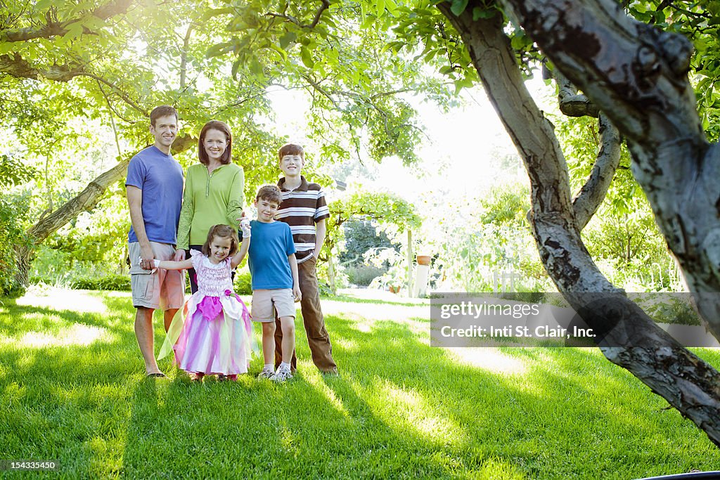 Happy family with tree children (4-5, 6-7, 12-13) in garden