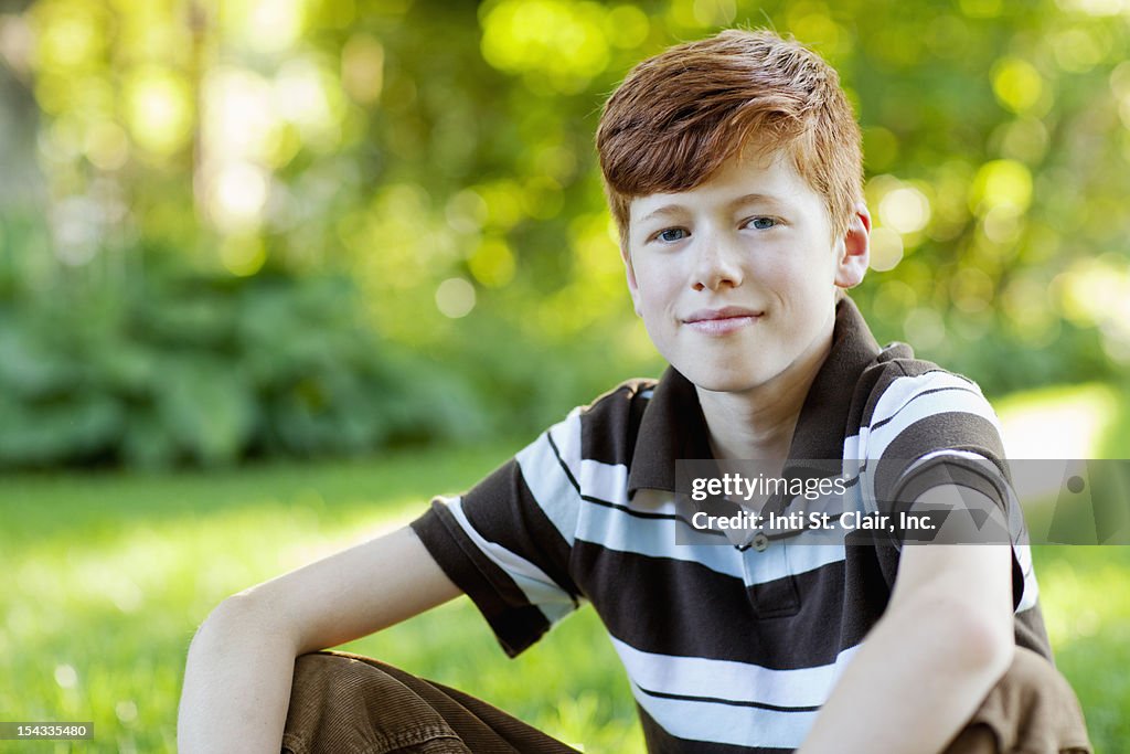 Boy (12-13) sitting in grass