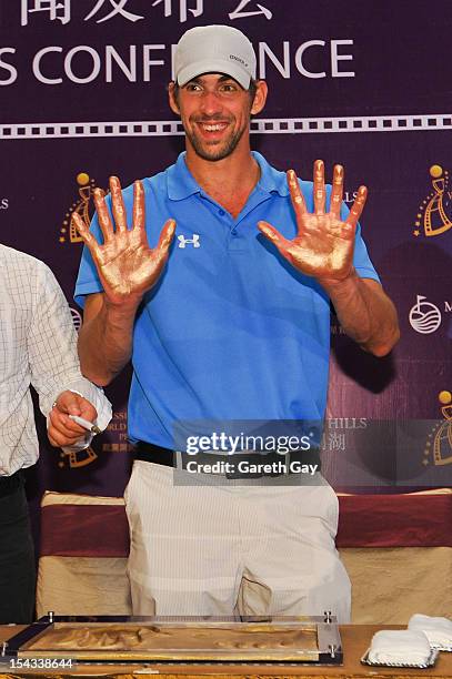 Michael Phelps shows the imprint of his hands at the Mission Hills World Celebrity Pro-Am press conference at the Mission Hills Haikou resort on...