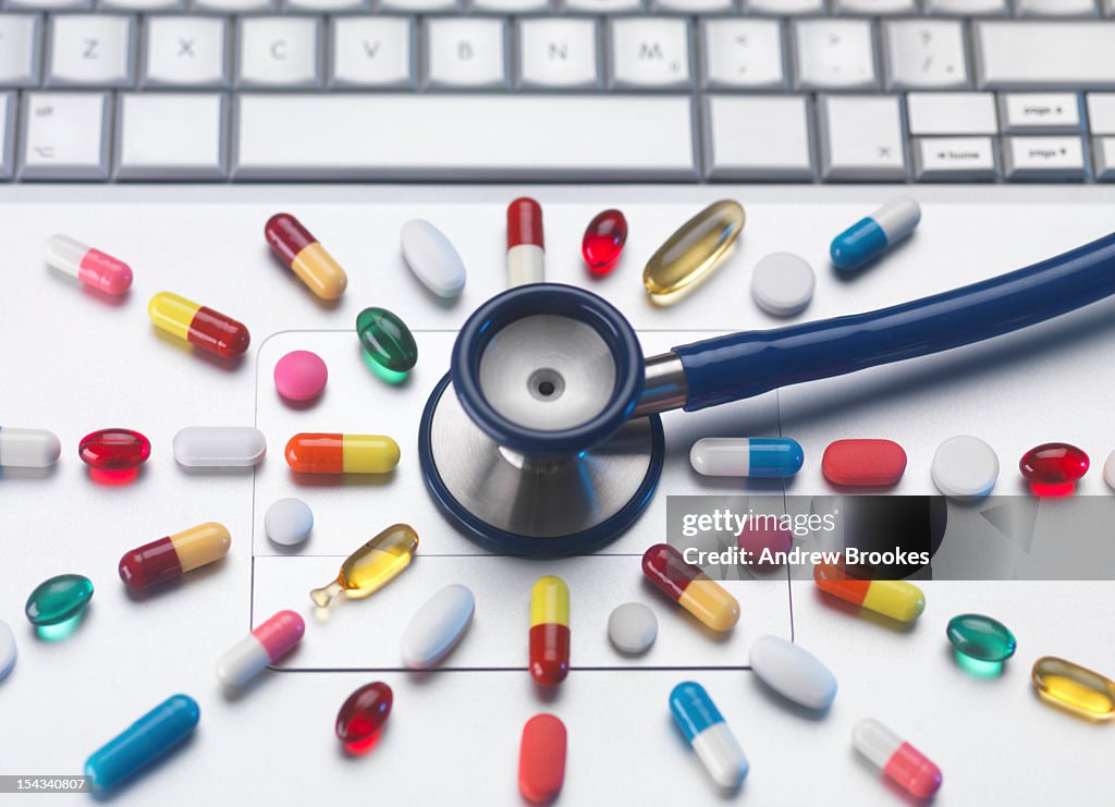 Pills and stethoscope on laptop