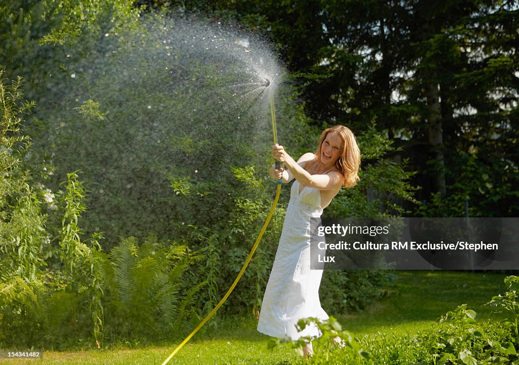 Woman spraying with hose in garden