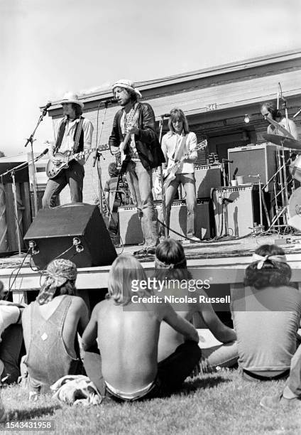 Bone Burnett, Bob Dylan, Mick Ronson, and an unidentified stagehand on the Rolling Thunder Revue tour at a free concert at the Gatesville State...