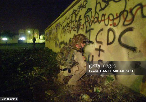Captain Jason Deel from the 4th Infantry Division Ironhorse replaces an anti-USA and ICDC graffiti with supporting ones during a joint night patrol...
