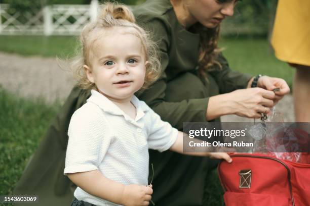 little boy standing near his mom in a park. - boy curly blonde stock pictures, royalty-free photos & images