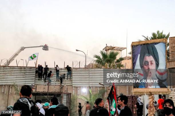 Supporters of Iraqi Shiite cleric Moqtada al-Sadr during a protest climb the fence outside the Swedish embassy in Baghdad on July 20, 2023 as...