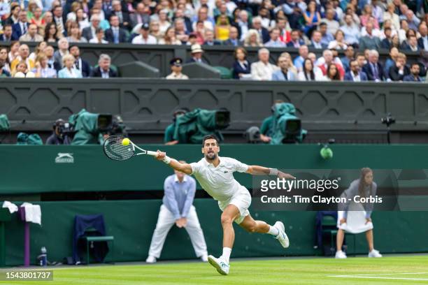 Novak Djokovic of Serbia stretches to reach a serve from Jannik Sinner of Italy in their Gentlemen's Singles semi-final match on Centre Court during...