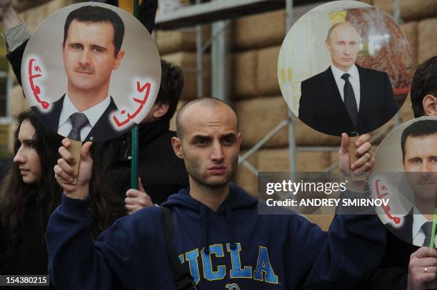 Man holds portrait of Russia's President Vladimir Putin and Syria's President Bashar al-Assad during a rally in support of Syrian regime in front of...