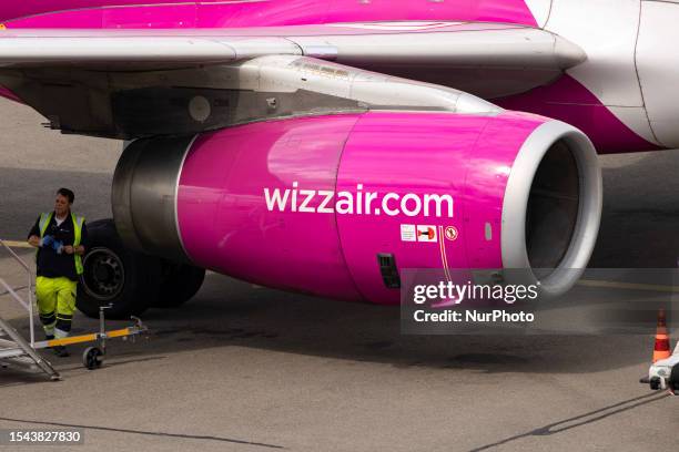 Closeup at a jet engine with wizzair logo next to an engineer. Wizz Air Airbus A320 aircraft as seen flying, landing and taxing at Eindhoven Airport...