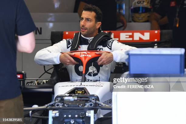 Alpha Tauri's Australian driver Daniel Ricciardo sits in his car at the Hungaroring race track in Mogyorod near Budapest on July 20 ahead of the...