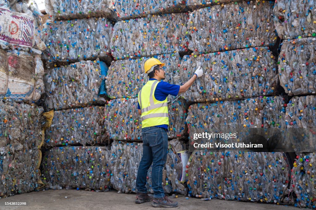 Worker at a recycling collection facility, Employees in a recycling plant inspecting the raw materials in the tablet.