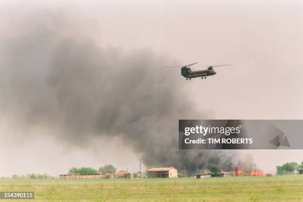 National Guard helicopter flies past the burning Branch Davidian cult compound in Waco, TX, 19 April 1993. The blaze ended a 51 day standoff between...
