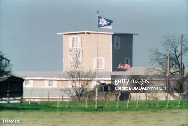 Bradley armored personel carrier flies the US flag 31 March 1993 in Waco as it passes near the front of the branch Davidian compound during talks...