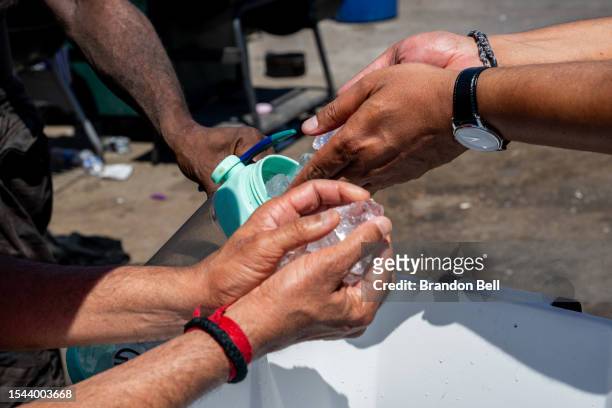 Volunteers with the Wells Fargo Technology Services help fill a homeless resident's water bottle on July 14, 2023 in Phoenix, Arizona. Today marks...