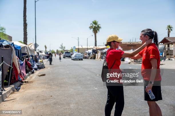 Volunteers with the Wells Fargo Technology Services share a moment together while passing out water bottles to homeless residents on July 14, 2023 in...
