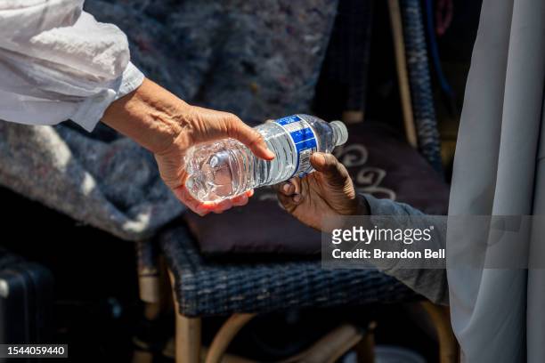 Volunteer with the Wells Fargo Technology Services passes out water to a homeless resident on July 14, 2023 in Phoenix, Arizona. Today marks the...