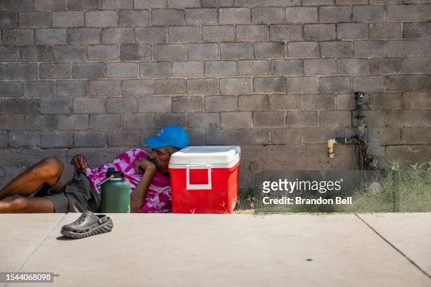 Person sleeps in the shade on July 14, 2023 in Phoenix, Arizona. Today marks the Phoenix area's 15th consecutive day of temperatures exceeding 110...
