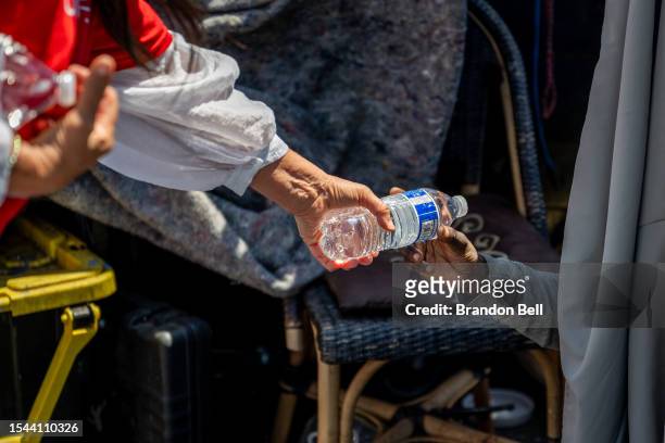 Volunteer with the Wells Fargo Technology Services passes out water to a homeless resident on July 14, 2023 in Phoenix, Arizona. Today marks the...