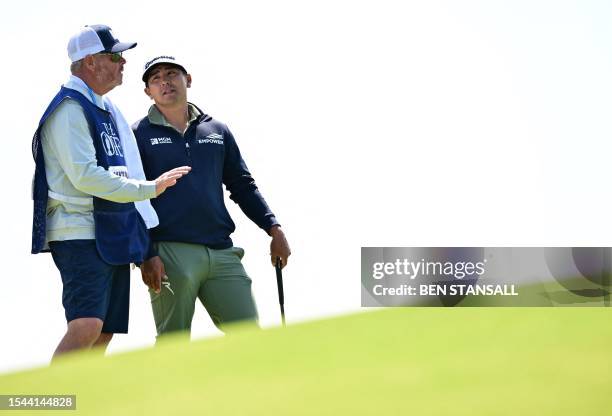 Golfer Kurt Kitayama talks with his caddie on the 17th green on day one of the 151st British Open Golf Championship at Royal Liverpool Golf Course in...