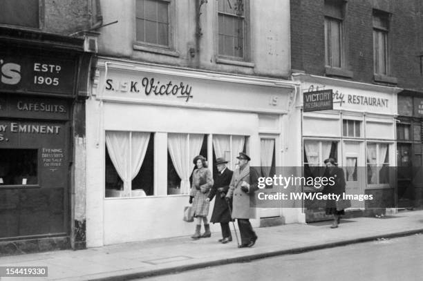 London In The Fifth Year Of War: Everyday Life In London, England, UK An army officer and several civilians walk past a restaurant called 'Victory'...