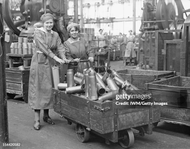 Women At Work During The First World War, Two women war workers push a truck load of shell cases in the New Case Shop at the Royal Arsenal, Woolwich,...