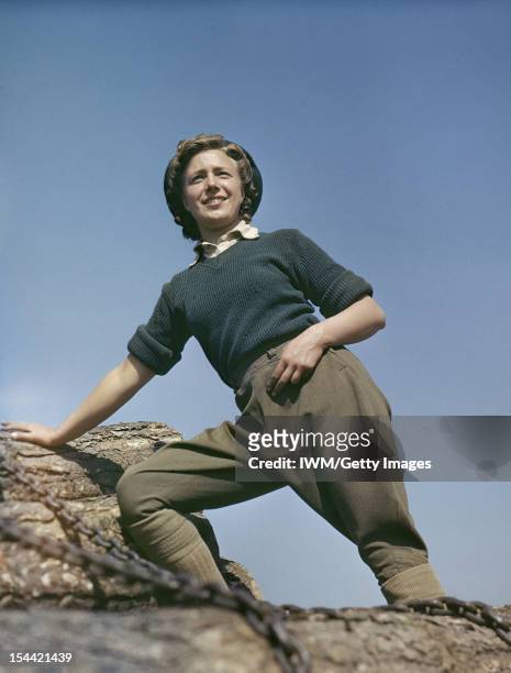 Women's Timber Corps Training Camp At Culford, Suffolk, Doreen Bacchus, a Land Army girl, standing on top of some tree trunks on a pull wagon, circa...