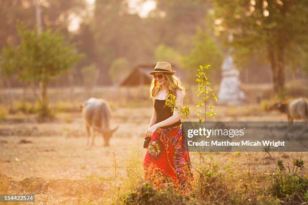 a girl walks through rice paddies and buffalo. - cambodia rice fields stock pictures, royalty-free photos & images