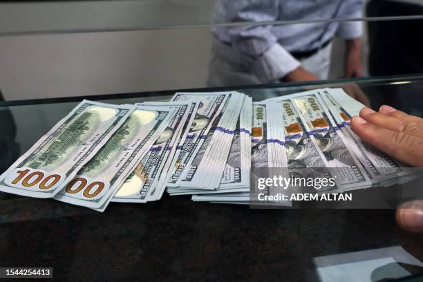 Teller shows US dollar bills at an exchange office in Ankara on July 20, 2023. Turkey's central bank hiked its main interest rate for the second...