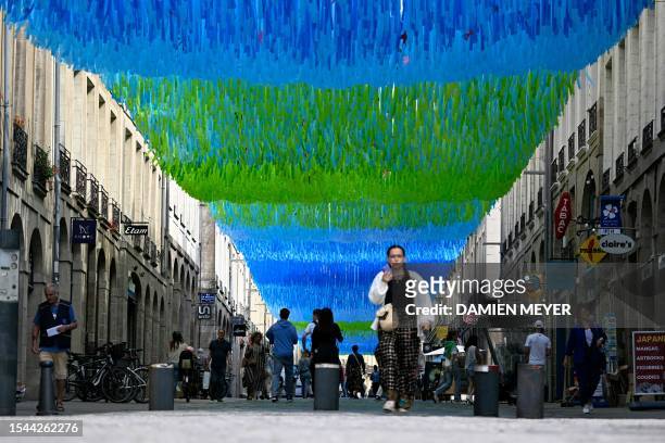 Woman walks under a shading device to fight excessive heat on a downtown shopping street in Rennes, western France on July 20 as Europe is hit by a...