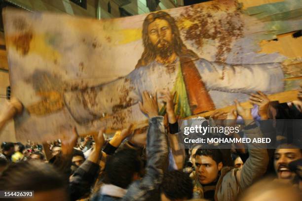 Egyptian Christians hold a blood-stained portrait of Jesus Christ during a protest late on January 2, 2011 outside the Al-Qiddissine church in...
