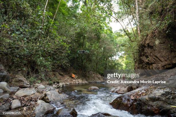 quadcopter drone flying with man and woman in the background in the middle of nature by minca river surrounded by lush sub tropical vegetation - magdalena bildbanksfoton och bilder