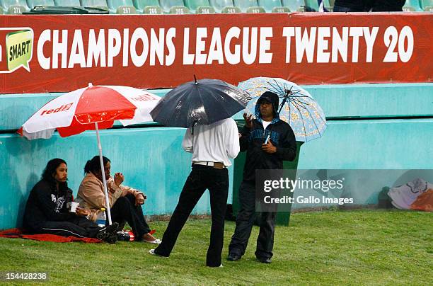 Fans shelter under umbrellas during the CLT20 match between Auckland Aces and Delhi Daredevils from Sahara Stadium Kingsmead on October 19, 2012 in...