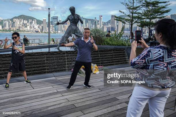 People take photos in front of the statue of Bruce Lee in Tsim Sha Tsui. The Hong Kong government commemorates the 50th anniversary of martial artist...