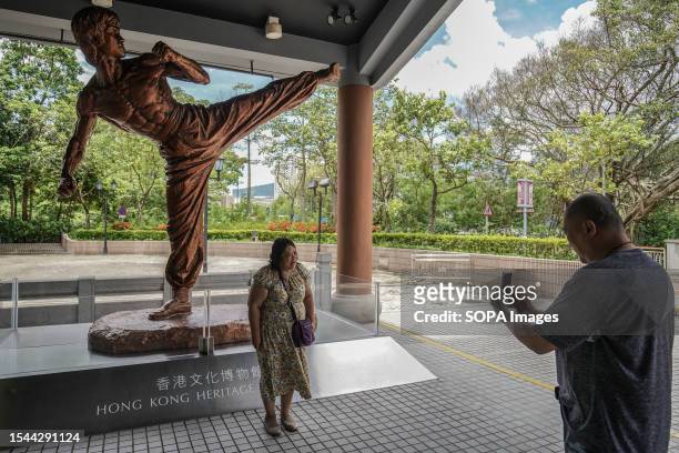 People take photos in front of the statue of Bruce Lee outside the Hong Kong Heritage Museum. The Hong Kong government commemorates the 50th...