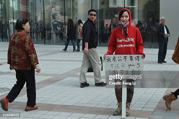 Chinese woman holds a sign which reads "My husband is not reliable, he doesn't buy me an iPhone 5, I'm looking for a rich man" outside a newly opened...