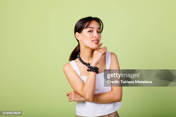 nature inspired elegance and fruit accessories: a beautiful brunette woman exuding a sense of unity with the natural world, wear a grape bracelet and grape berry beads in a vibrant green studio. - sleeveless stock pictures, royalty-free photos & images