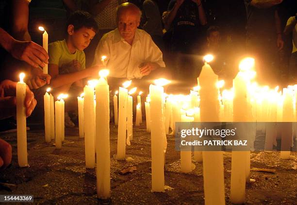 Lebanese boy and his grand father light candles during a vigil in Beirut on October 20 near the site of a car bomb attack the day before in which...