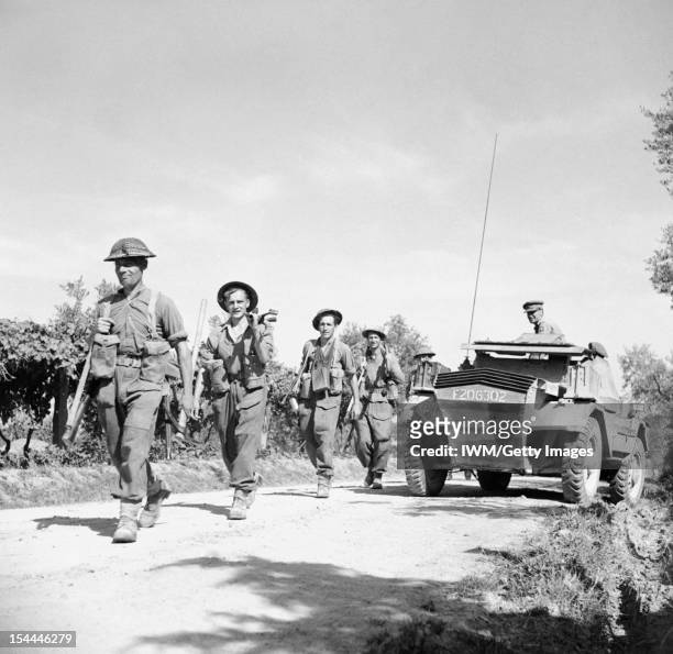 The British Army In Italy 1944, British Infantry move up past a Daimler scout car during the advance of 78th Division, 30 June 1944.