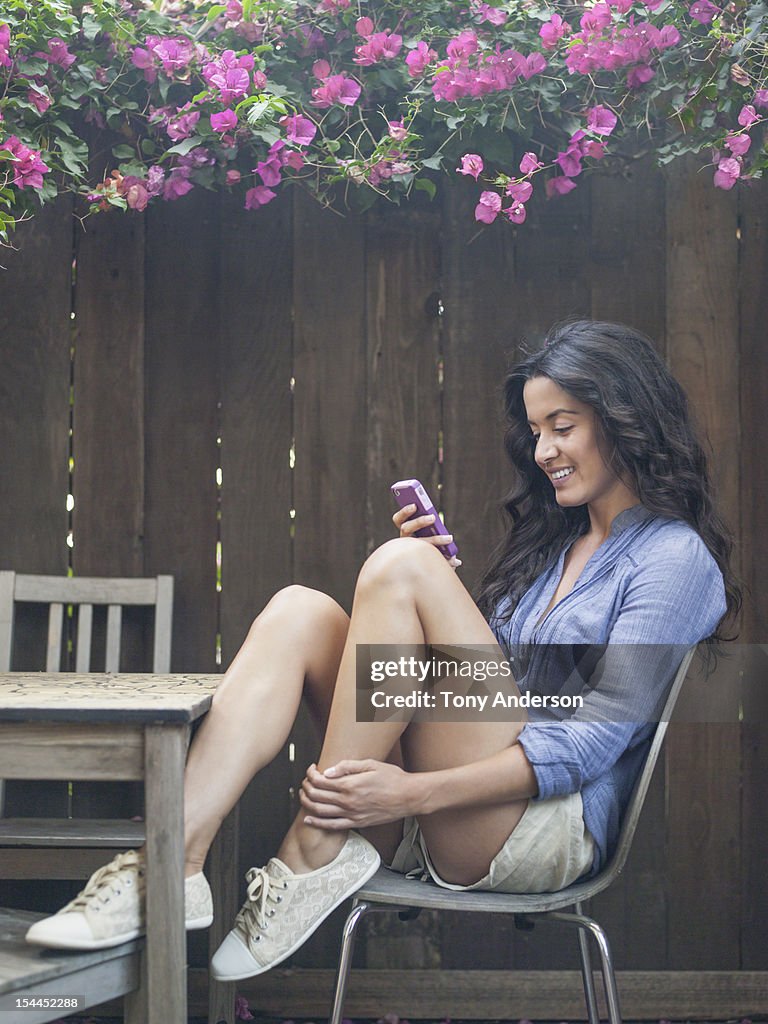Woman checking mobile device in back yard