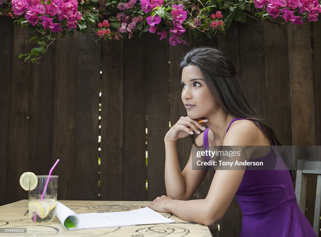 Young woman with pencil and paper in back yard