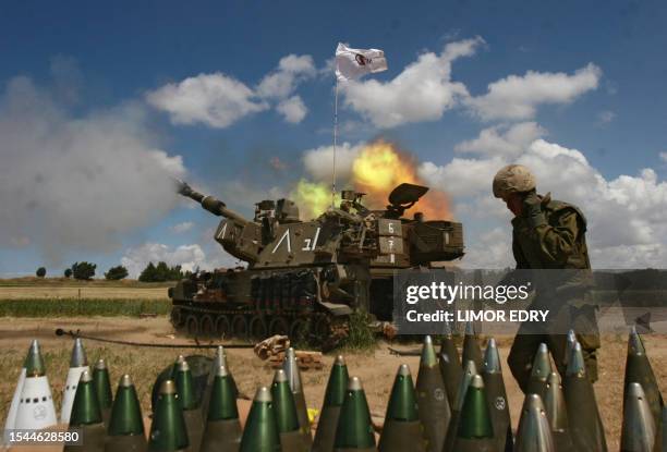 An Israeli soldier walks behind tank rockets as a mobile artillery unit fires a shell towards the Gaza Strip from a position near Kibbutz Nahal Oz in...