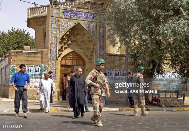 Sunni worshippers walk out form al-Shawi mosque in Baghdad under the protection of an Iraqi soldier after performing Friday noon prayer, 24 March...