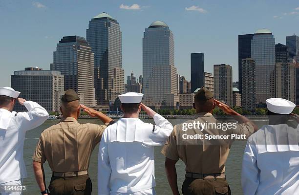 Navy sailors and U.S. Marines salute while passing Ground Zero, the site of the World Trade Center attacks, aboard the USS Iwo Jima May 22, 2002 in...