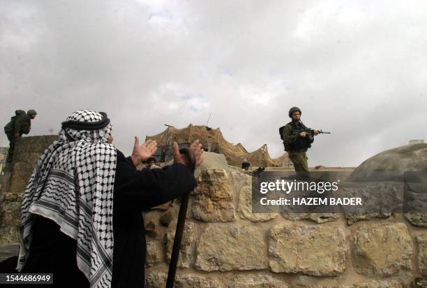 An elderly Palestinian asks Israeli troops for help Jewish settlers ransacked shops in the market of the divided city of Hebron, 15 January 2006....