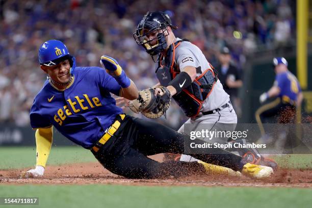 Julio Rodriguez of the Seattle Mariners scores past Jake Rogers of the Detroit Tigers at home plate during the eighth inning at T-Mobile Park on July...